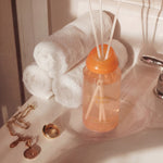LEAFI Shadows Freesia & Pear home diffuser (200ml) on a bathroom sink with towels and jewelry.