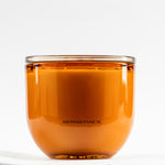 Close-up of LEAFI Allure Orange & Sandalwood candle (400g) showing a cotton wick in an amber glass jar on a white background.